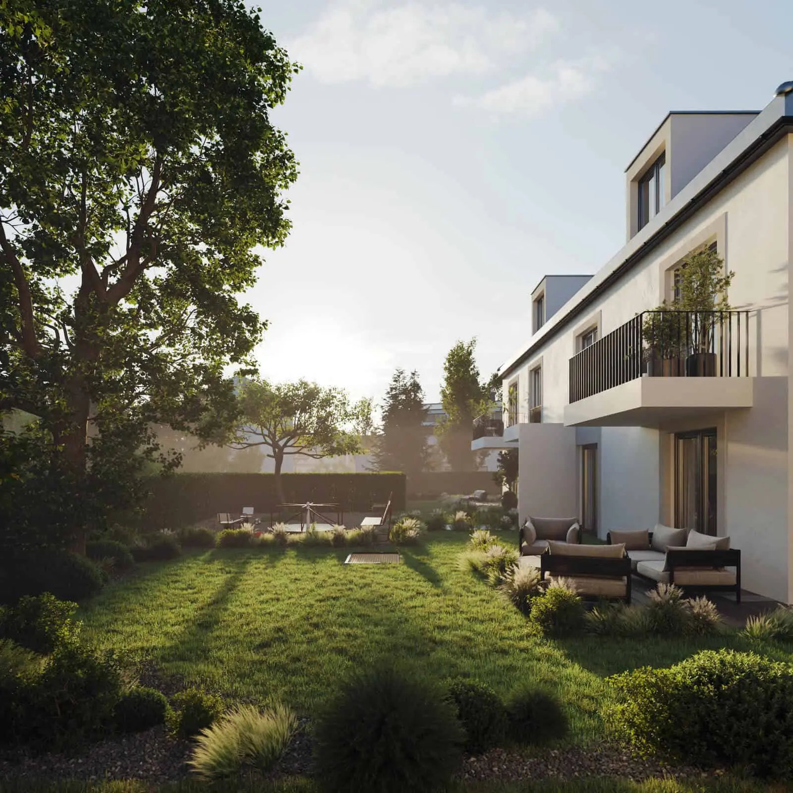 Modernes, weißes, zweistöckiges Haus mit Balkonen, großen Fenstern und einem großzügigen, grünen Garten mit Sitzgelegenheiten im Freien und Grünpflanzen, fotografiert bei Sonnenuntergang.