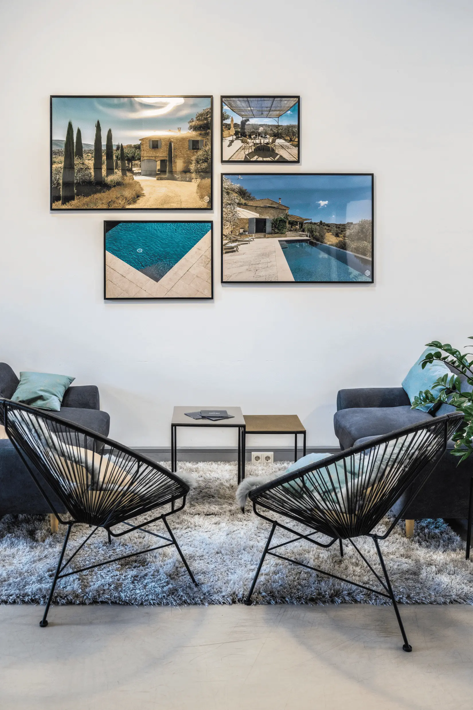 Stilvolles Wohnzimmer mit zwei Stühlen vor einem kleinen Tisch, flankiert von zwei Sofas. Gerahmte Landschaftsfotos sind an einer weißen Wand über einem zotteligen Teppich arrangiert und schaffen ein gemütliches Ambiente, das durch sein harmonisches Design die Geschichte von „Über uns“ erzählt.