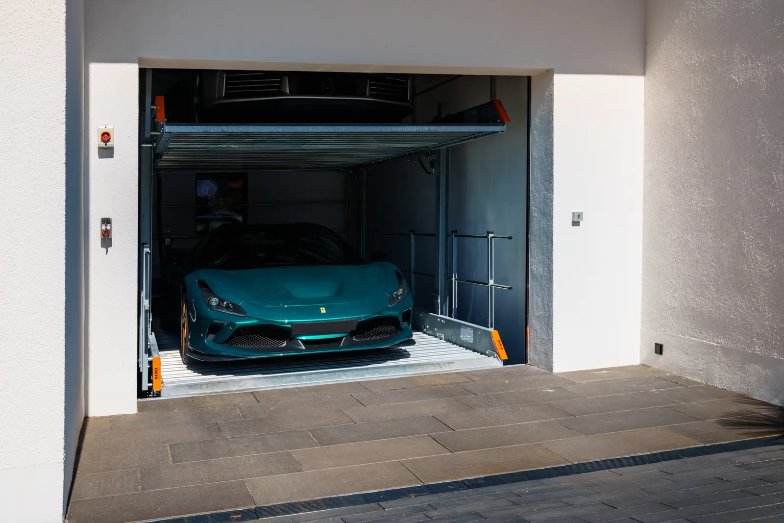 Ein türkisfarbener Ferrari stand auf der unteren Ebene eines zweistöckigen Autolifts für Privathaushalte in einer Garage.